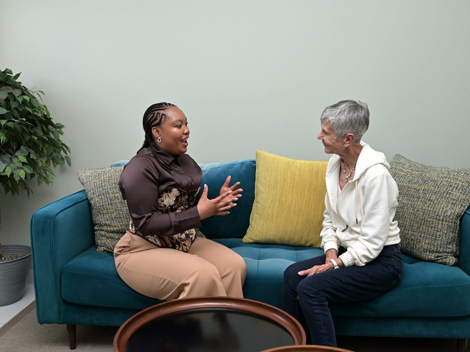 A HospiceWits team member in conversation with an older woman on a sofa