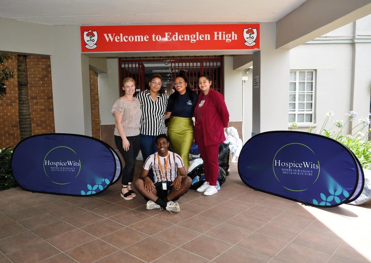 HospiceWits volunteers and staff at a donation drive at Edenglen High School, between two HospiceWits banners
